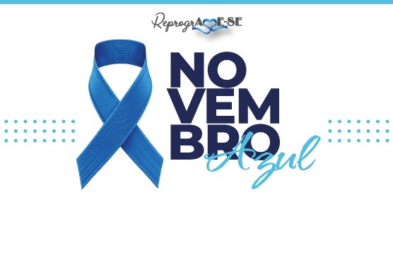 A imagem apresenta uma fita azul, símbolo da campanha Novembro Azul, que é voltada para a conscientização sobre a saúde do homem, especialmente em relação ao câncer de próstata. Ao lado da fita, está escrito "NOVEMBRO Azul" em letras grandes, com "NOVEMBRO" em azul escuro e "Azul" em azul claro. Acima, há o texto "ReprogrAME-SE" com um coração azul substituindo a letra "A". Há também pequenos pontos azuis decorativos ao lado da fita.