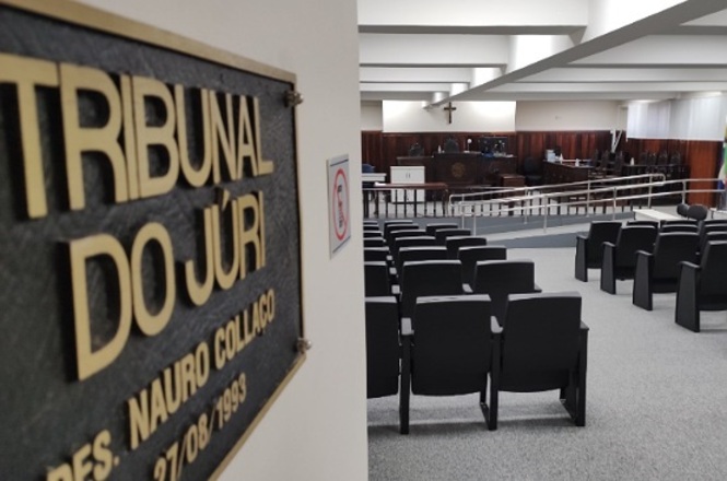 A imagem mostra uma sala de Tribunal do Júri. À direita, é possível ver cadeiras organizadas para o público e, ao fundo, a área principal onde ocorrem os julgamentos, com uma bancada elevada e uma cruz na parede.