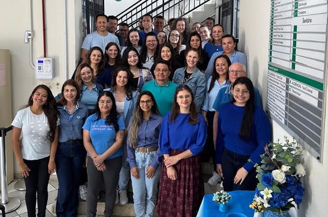 A imagem mostra um grupo de pessoas reunidas posando para a foto. Elas estão em pé em uma escada. Todos vestem azul, em menção ao novembro azul.