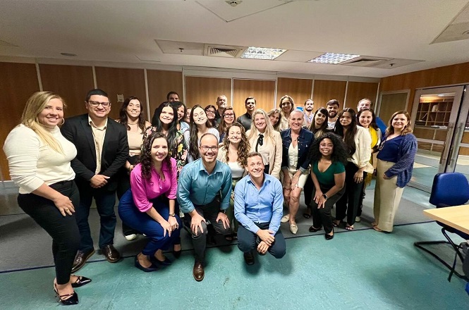 A imagem mostra um grupo de servidoras do judiciário catarinense posando para uma foto. Algumas pessoas estão em pé, enquanto outras estão agachadas na frente para que todos fiquem visíveis na fotografia.
