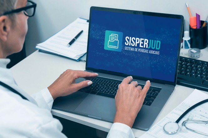 A imagem mostra uma pessoa usando um laptop em uma mesa de escritório. Na tela do laptop, está aberto um programa chamado "SISPERJUD", que significa "Sistema de Perícias Judiciais". Ao lado do laptop, há uma prancheta com papéis e uma caneta, além de um estetoscópio, sugerindo que a pessoa pode ser um profissional da área de saúde ou jurídica. A pessoa está usando óculos e parece estar concentrada no que está fazendo no computador.