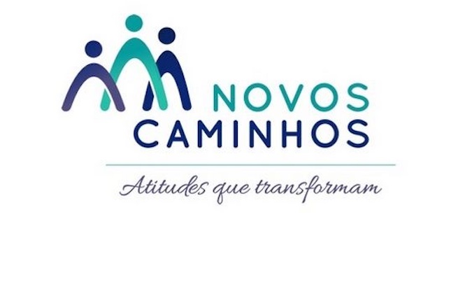 A imagem é o logotipo do "Novos Caminhos". Ela possui três figuras estilizadas representando pessoas em tons de azul, formando uma espécie de "M". Abaixo das figuras, está escrito "NOVOS CAMINHOS" em letras maiúsculas. Mais abaixo, em fonte cursiva, aparece a frase "Atitudes que transformam".