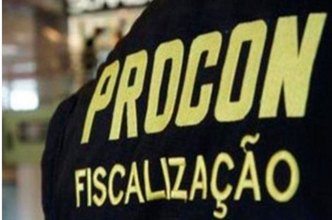 A imagem mostra parte de um uniforme ou colete com as palavras "PROCON FISCALIZAÇÃO" escritas em letras grandes e amarelas. "PROCON" refere-se ao órgão de proteção e defesa do consumidor no Brasil, e "FISCALIZAÇÃO" indica que é relacionado a atividades de inspeção ou supervisão. O fundo da imagem está desfocado, destacando o texto.