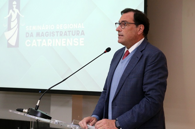 Foto horizontal: Francisco Oliveira Neto discursa ao microfone em seminário da magistratura catarinense.