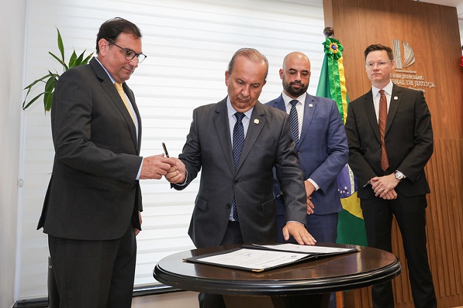 Foto horizontal: de gravata amarela, Francisco Oliveira Neto acompanha Jorginho Mello em assinatura oficial no TJSC.