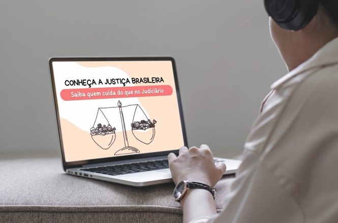 A imagem mostra uma pessoa usando um laptop. Na tela do laptop, há uma ilustração com uma balança da justiça e o texto "CONHEÇA A JUSTIÇA BRASILEIRA" e "Saiba quem cuida do que no Judiciário". A pessoa está usando fones de ouvido e aparenta estar prestando atenção na tela.