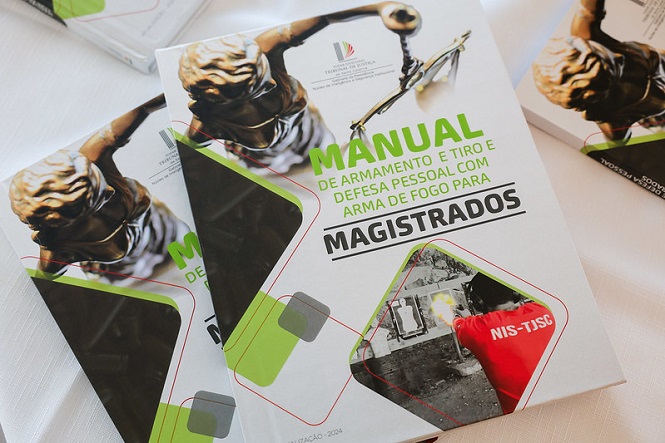 A imagem mostra um manual intitulado "Manual de Armamento e Tiro e Defesa Pessoal com Arma de Fogo para Magistrados". Na capa, há uma imagem da estátua da Justiça, que geralmente representa imparcialidade e integridade. O design inclui formas geométricas em verde e cinza, além de uma foto relacionada ao tema do manual. O manual parece ser direcionado a magistrados e aborda temas de armamento e defesa pessoal.