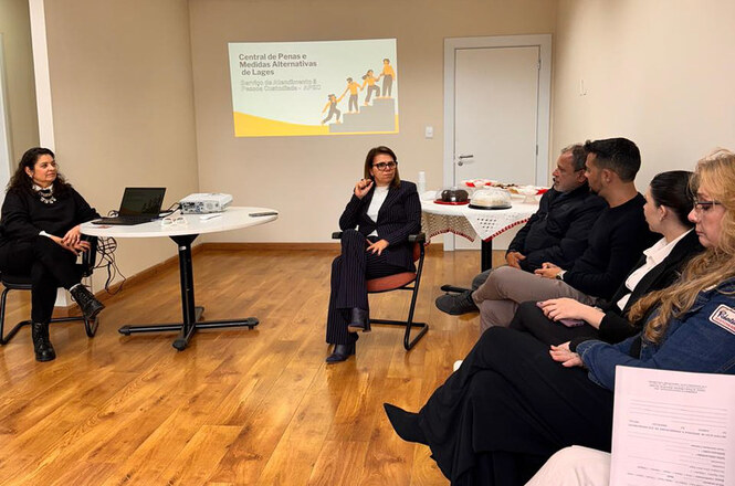Reunião em círculo com foco na apresentação “Central de Penas e Medidas Alternativas de Lages”. Ambiente formal e interativo, voltado ao aprendizado.