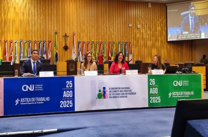 A imagem mostra quatro pessoas em uma mesa de conferência durante o II Encontro Nacional do Comitê dos Direitos de Pessoas com Deficiência, em um auditório institucional com bandeiras e crucifixo, transmitindo um ambiente profissional e solene.