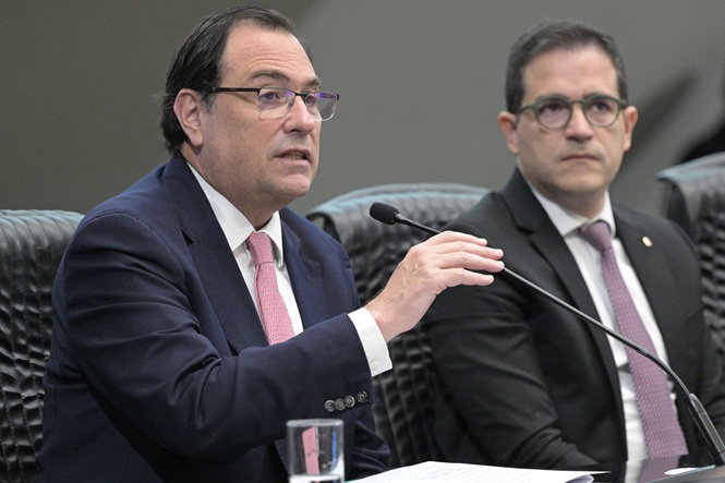 Foto horizontal: Francisco Oliveira Neto fala ao microfone durante reunião institucional ao lado de autoridade.