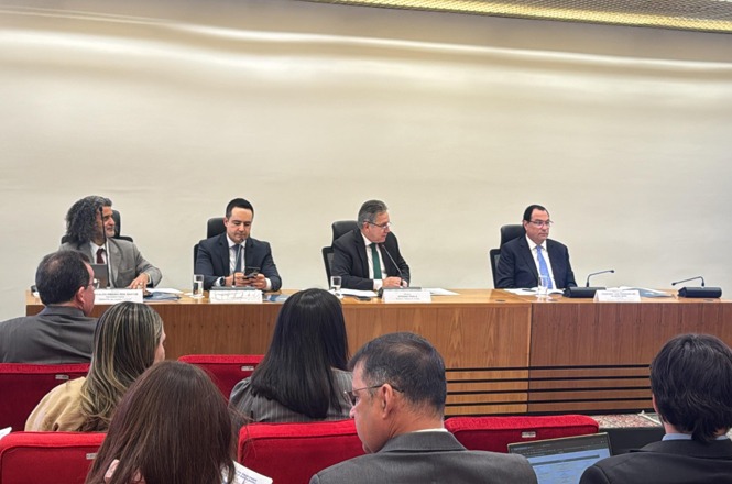Foto horizontal: Francisco Oliveira Neto, de gravata azul, participa de mesa institucional em auditório.