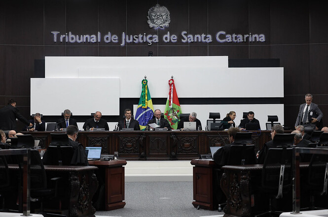 Foto colorida: desembargadores à mesa no plenário do TJSC, ambiente institucional interno, sessão judicial, deliberando processos