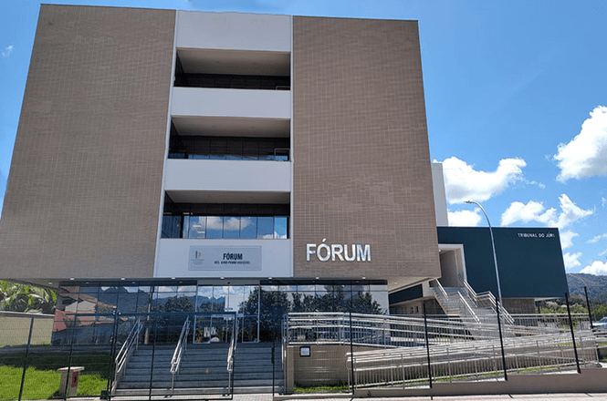 Prédio do fórum, em área urbana, fachada institucional, serviço público, exibindo arquitetura em bege e branco