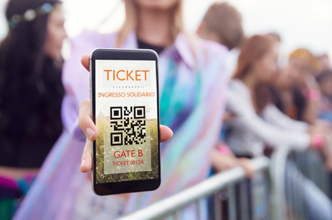 Uma pessoa segura um smartphone exibindo um bilhete digital para a porta B em um evento, com uma multidão de pessoas desfocadas ao fundo.
