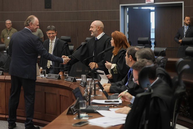 O presidente do Tribunal de Justiça de Santa Catarina (TJSC), desembargador Rubens Schulz, cumprimentando autoridades à mesa, plenário judicial interno, sessão institucional