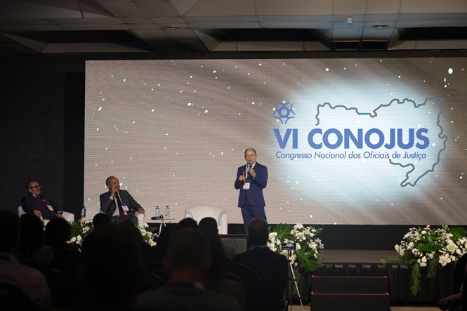 Arte gráfica: cartaz do VI CONOJUS com mapa do Brasil, fundo desfocado, congresso jurídico, divulgando evento em azul, branco e dourado