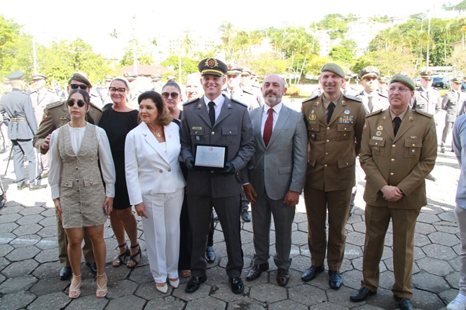 Foto horizontal: desembargador André Luiz Dacol entre militares em solenidade, grupo reunido ao ar livre, tons claros e verde.