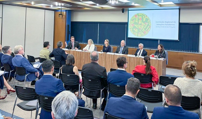 Foto horizontal: autoridades participam de reunião sobre regularização fundiária em auditório institucional.