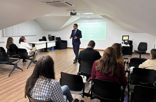 Foto horizontal: palestrante orienta público em sala durante apresentação sobre violência e denúncia.