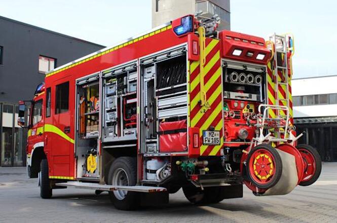 Foto horizontal: caminhão do Corpo de Bombeiros com compartimentos abertos, equipamentos visíveis, ambiente externo, cores vermelho e amarelo.
