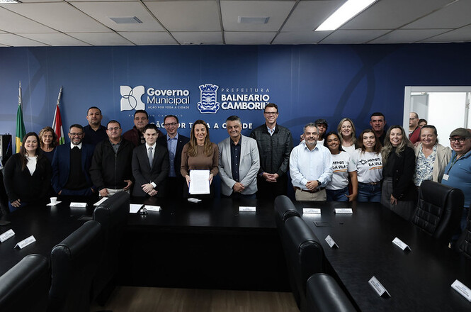 Foto horizontal: grupo posa em sala institucional com representantes do Governo Municipal e TJSC, registro coletivo, clima de parceria e cooperação.