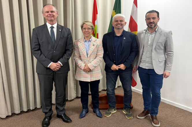 Foto horizontal: o desembargador Rubens Schulz posa ao lado do prefeito e da vice-prefeita de Blumenau, ambiente institucional, clima de parceria e cooperação.