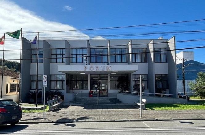 Foto horizontal: fachada do fórum de São Francisco do Sul, prédio institucional em destaque, ambiente externo, clima de acesso à Justiça.