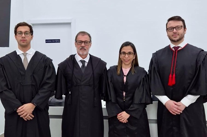 Foto horizontal: magistrados posam em trajes forenses em ambiente institucional, registro formal, clima de solenidade e atuação jurídica.