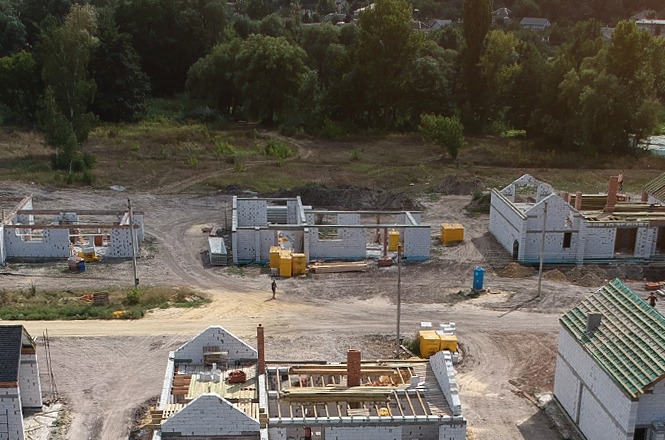 Foto horizontal: área em construção com edificações em fase inicial, terreno amplo ao redor, clima de desenvolvimento urbano e expansão.