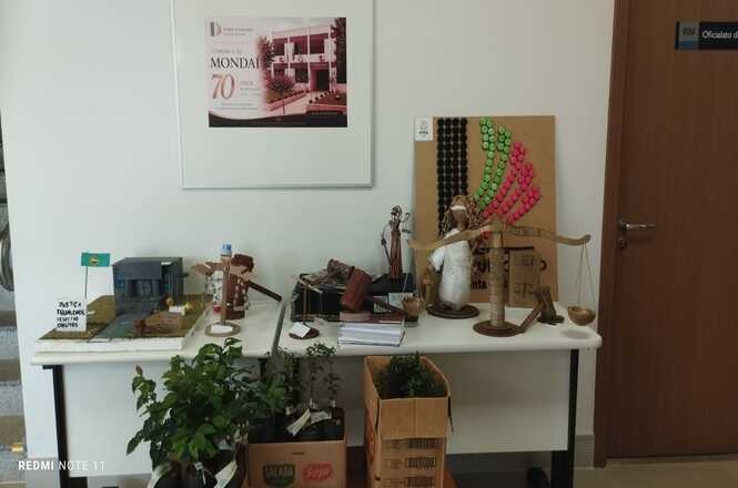Foto horizontal: mesa com objetos decorativos e peças artesanais em ambiente interno, elementos culturais em destaque, clima de memória e identidade local.