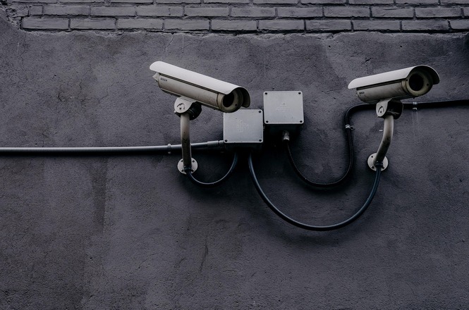 Foto horizontal: câmeras de segurança instaladas em parede externa, equipamentos em destaque, clima de vigilância, monitoramento e proteção.