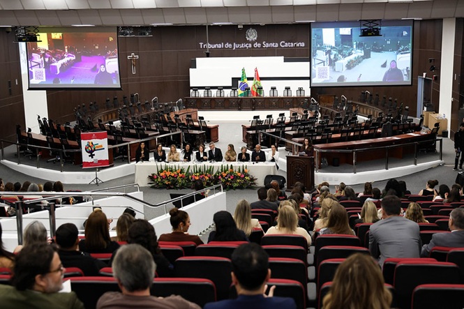 Foto horizontal: plenário do Tribunal de Justiça de Santa Catarina recebe público em evento sobre os 20 anos da Lei Maria da Penha, mesa de autoridades ao centro, clima de conscientização, debate e mobilização institucional.