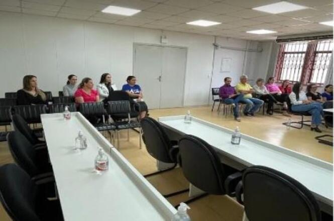 Foto horizontal: participantes acompanham reunião em auditório, durante atividade de capacitação e diálogo com a comunidade em ambiente institucional.