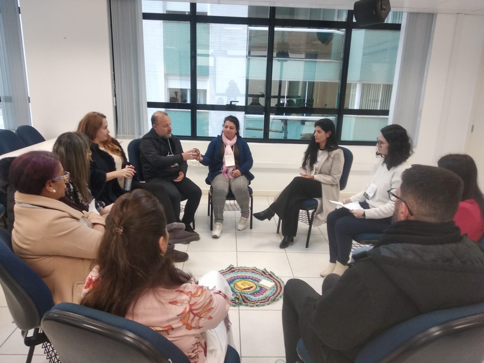 Foto horizontal: participantes reunidos em círculo durante atividade de escuta e diálogo promovida pelo Poder Judiciário, em encontro voltado ao acolhimento, fortalecimento de vínculos e construção coletiva de soluções.