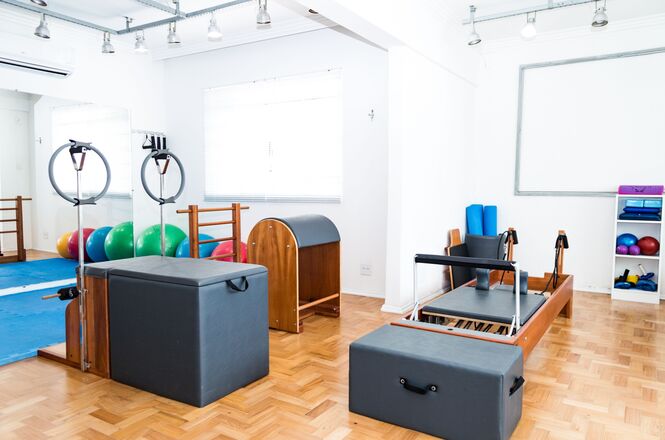 Foto horizontal: sala equipada com aparelhos de pilates e fisioterapia utilizados em atividades de reabilitação e condicionamento físico.