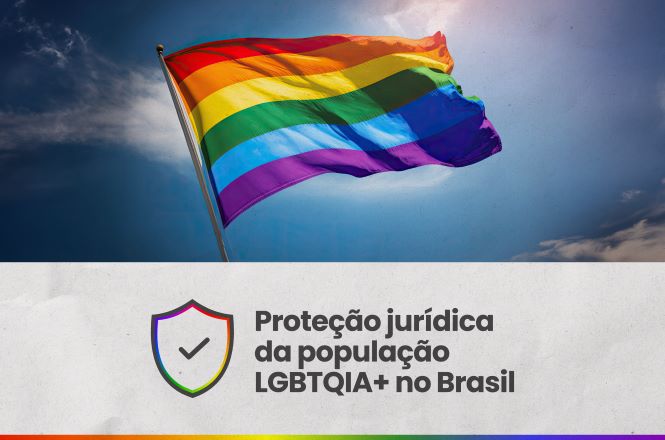 Arte gráfica composta por duas partes. Na parte superior, há uma fotografia de uma bandeira do orgulho LGBTQIA+ ondulando ao vento, com as cores do arco-íris em destaque sobre um céu azul com algumas nuvens. Na parte inferior, sobre fundo claro, aparece à esquerda um ícone de escudo com um símbolo de verificação no centro e contorno nas cores do arco-íris. Ao lado, em letras escuras, está o texto: “Proteção jurídica da população LGBTQIA+ no Brasil”. Na borda inferior da arte, há uma faixa horizontal nas cores da bandeira LGBTQIA+.