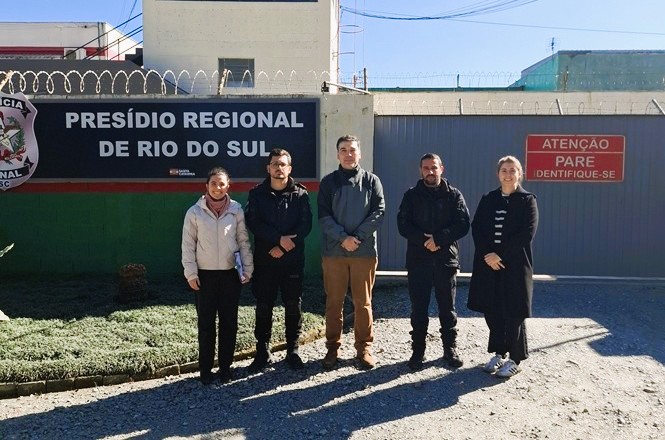 Foto horizontal: representantes do Poder Judiciário posam em frente ao Presídio Regional de Rio do Sul durante visita institucional voltada ao acompanhamento e fortalecimento da articulação entre os sistemas de Justiça e administração prisional.