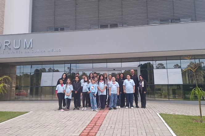 Foto horizontal: grupo de estudantes e acompanhantes posa em frente ao Fórum durante visita educativa às instalações do Poder Judiciário.