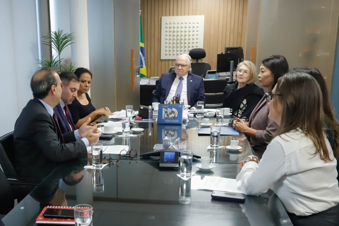 Foto horizontal: autoridades e representantes de instituições participam de reunião institucional em torno de mesa de trabalho, durante discussão de pautas relacionadas à proteção da infância e da adolescência.