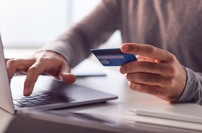 Pessoa utiliza cartão bancário para realizar compra ou pagamento em computador portátil.