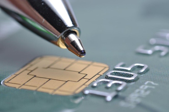 Caneta aponta para chip de cartão bancário, em referência a pagamentos e operações financeiras eletrônicas.