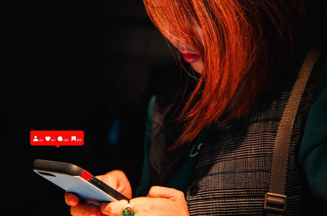 Pessoa utiliza celular com ícones de redes sociais, em referência ao uso das plataformas digitais.