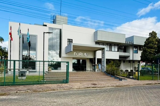Fachada do Fórum da Comarca de Içara, com entrada principal, mastros e área frontal ajardinada.