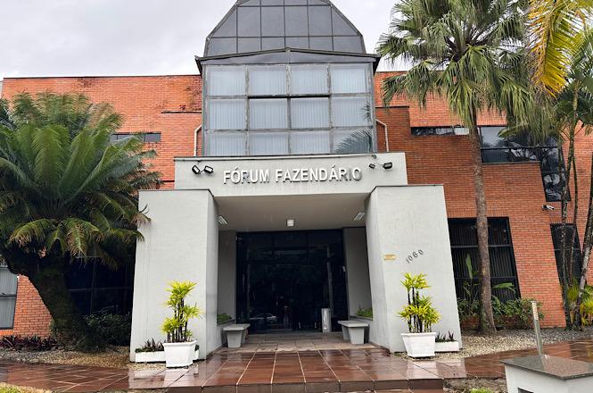 Fachada do Fórum Fazendário de Joinville, com acesso principal, palmeiras e jardim frontal.