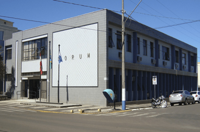 Fachada do Fórum, edifício de dois pavimentos em esquina urbana sob céu azul.