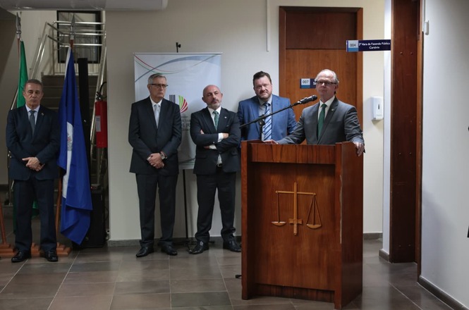 Presidente do TJSC discursa em cerimônia, ao púlpito, acompanhado por autoridades