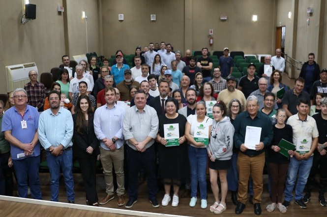 Beneficiários e autoridades registram entrega de títulos de regularização fundiária em foto coletiva.
