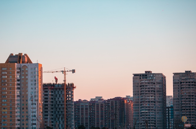 Prédios residenciais e obra em construção compõem a paisagem urbana sob céu ao entardecer.