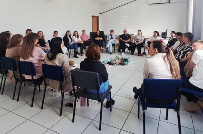 Foto horizontal: participantes estão sentados em círculo durante roda de conversa, em atividade voltada ao diálogo, à escuta e à troca de experiências.