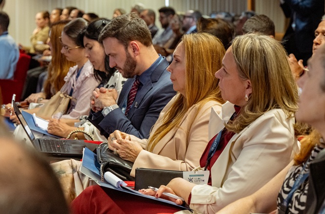 Foto horizontal: participantes acompanham atentamente as atividades durante evento realizado em auditório.